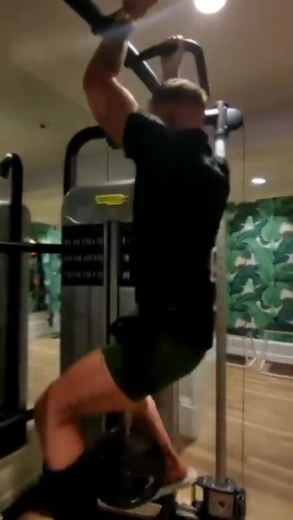 Conor McGregor performs weighted pull ups while wearing a protective boot to protect his broken leg.