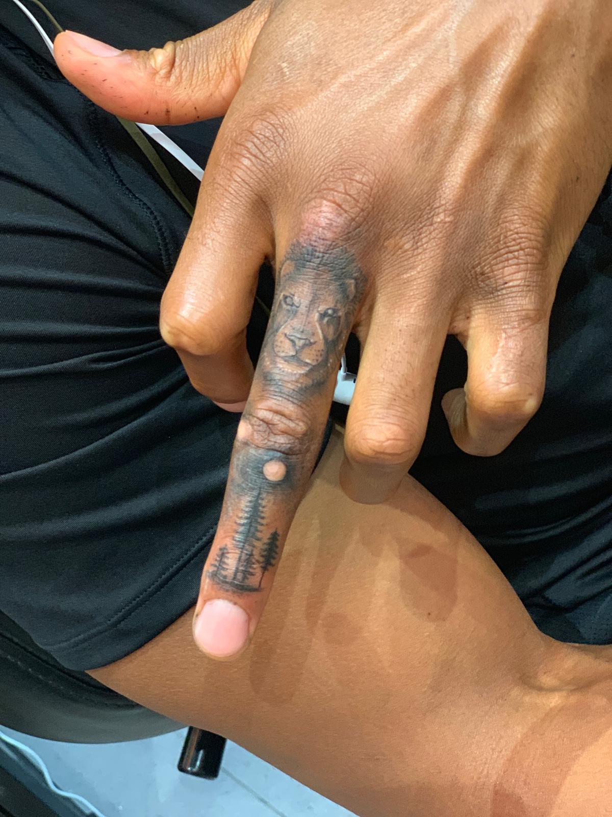 Joshua had a lion and a forest inked on his middle finger to cover his calluses