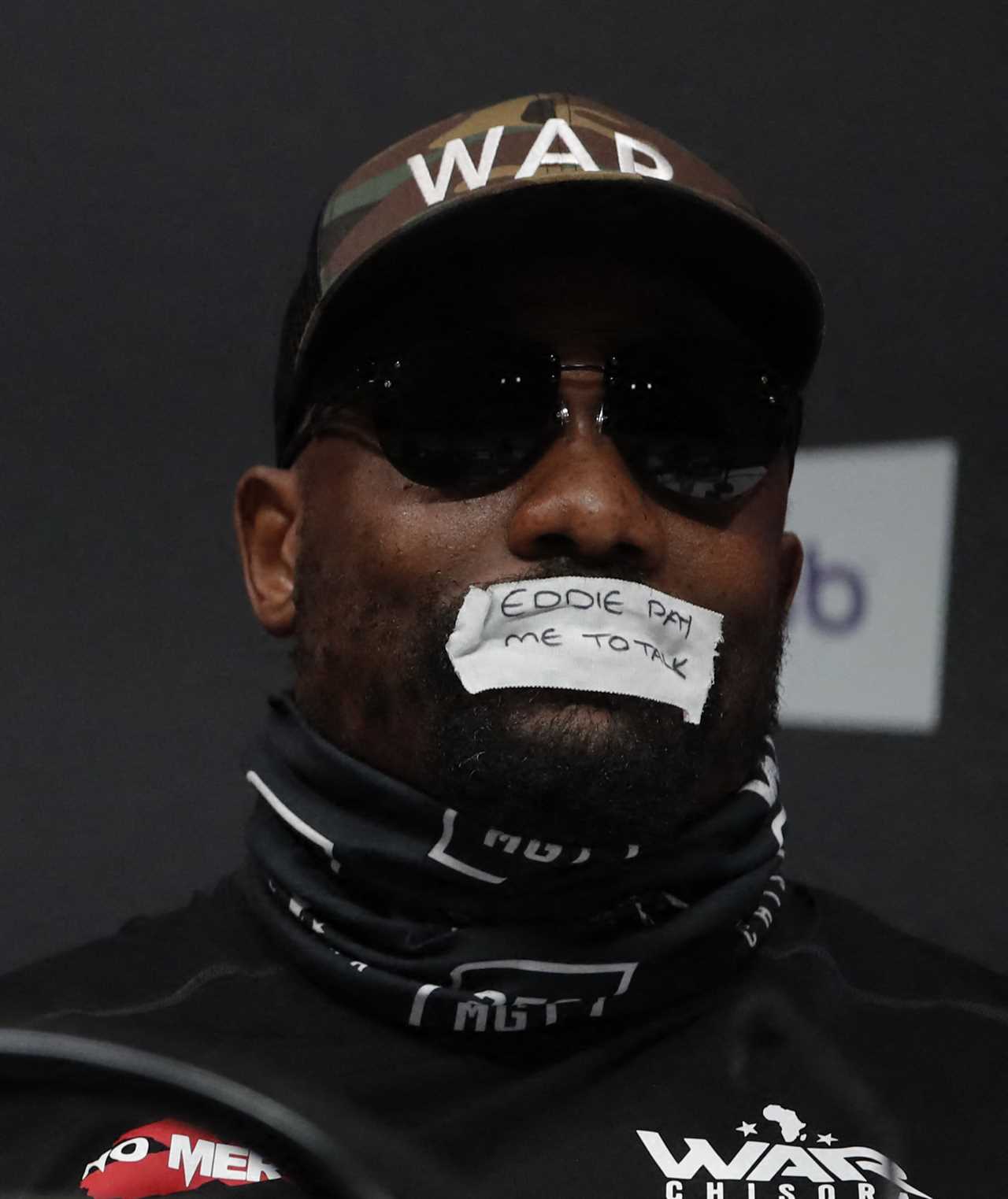 Derek Chisora taps his mouth with a taunting message for Eddie Hearn during a bizarre press conference about Joseph Parker fight