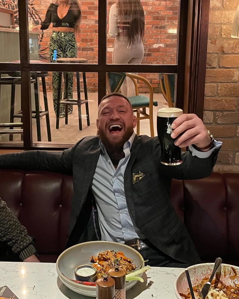 Conor McGregor, a smiling man, enjoys a pint at his Black Forge Inn bar just hours after the petrol bomb attack.