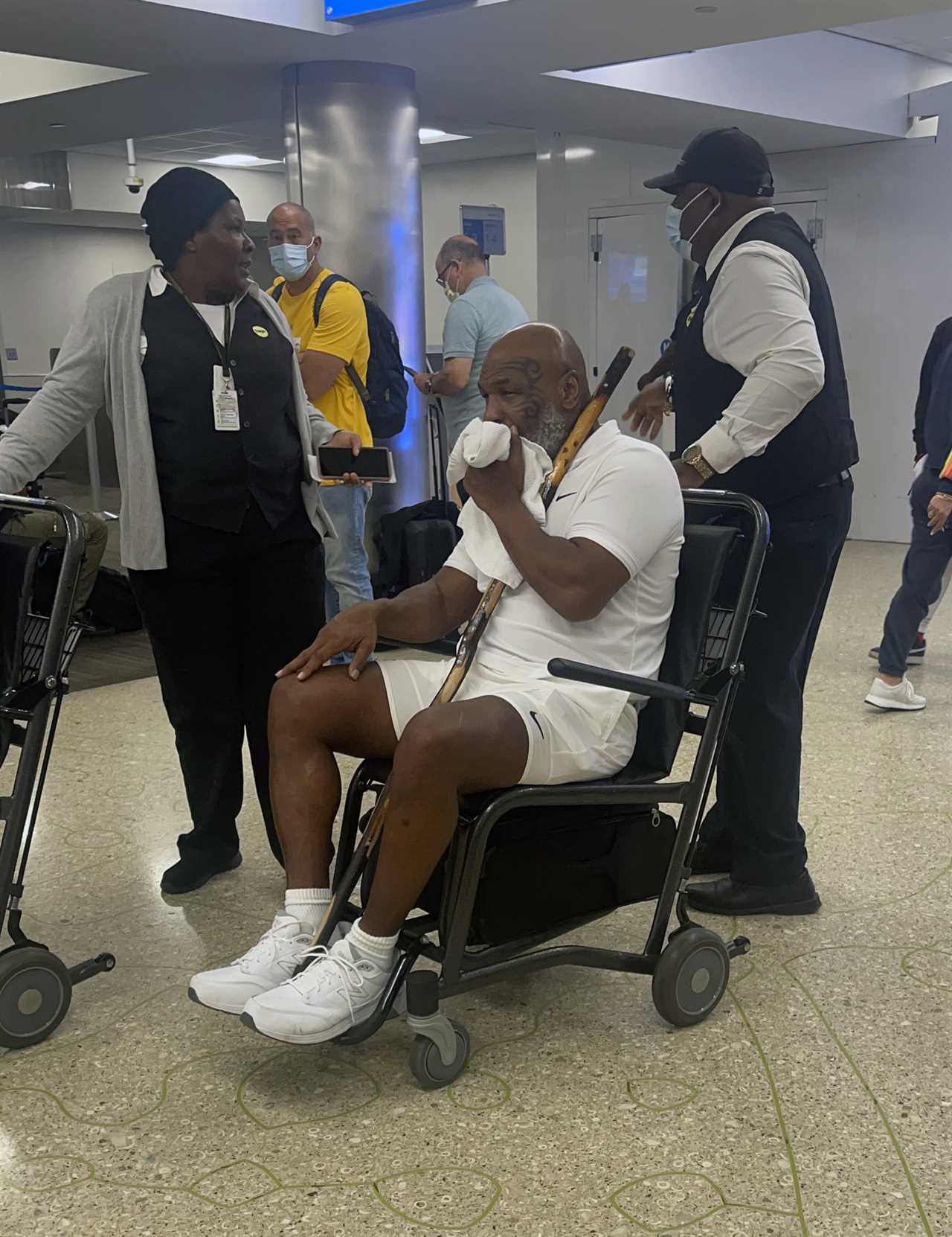 Mike Tyson, 56 years old, is seen holding a walking stick and in a wheelchair as he makes his way through Miami Airport.