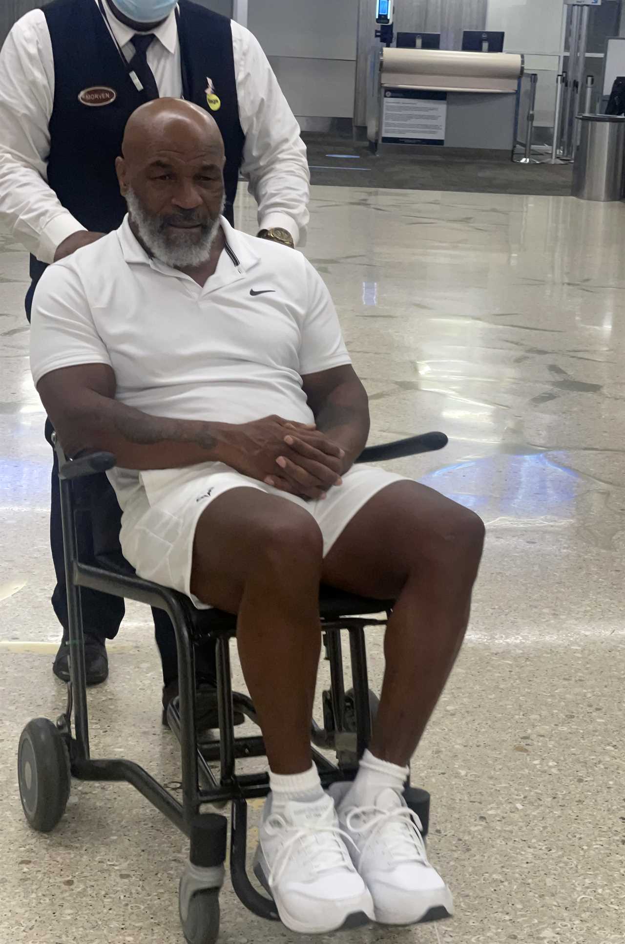 Mike Tyson, 56 years old, is seen holding a walking stick and in a wheelchair as he makes his way through Miami Airport.