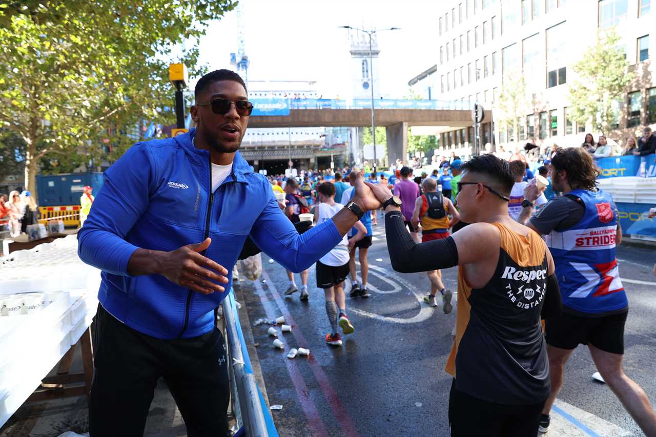 As Tyson Fury talks, Anthony Joshua gives drinks to London Marathon runners who stopped for selfies.