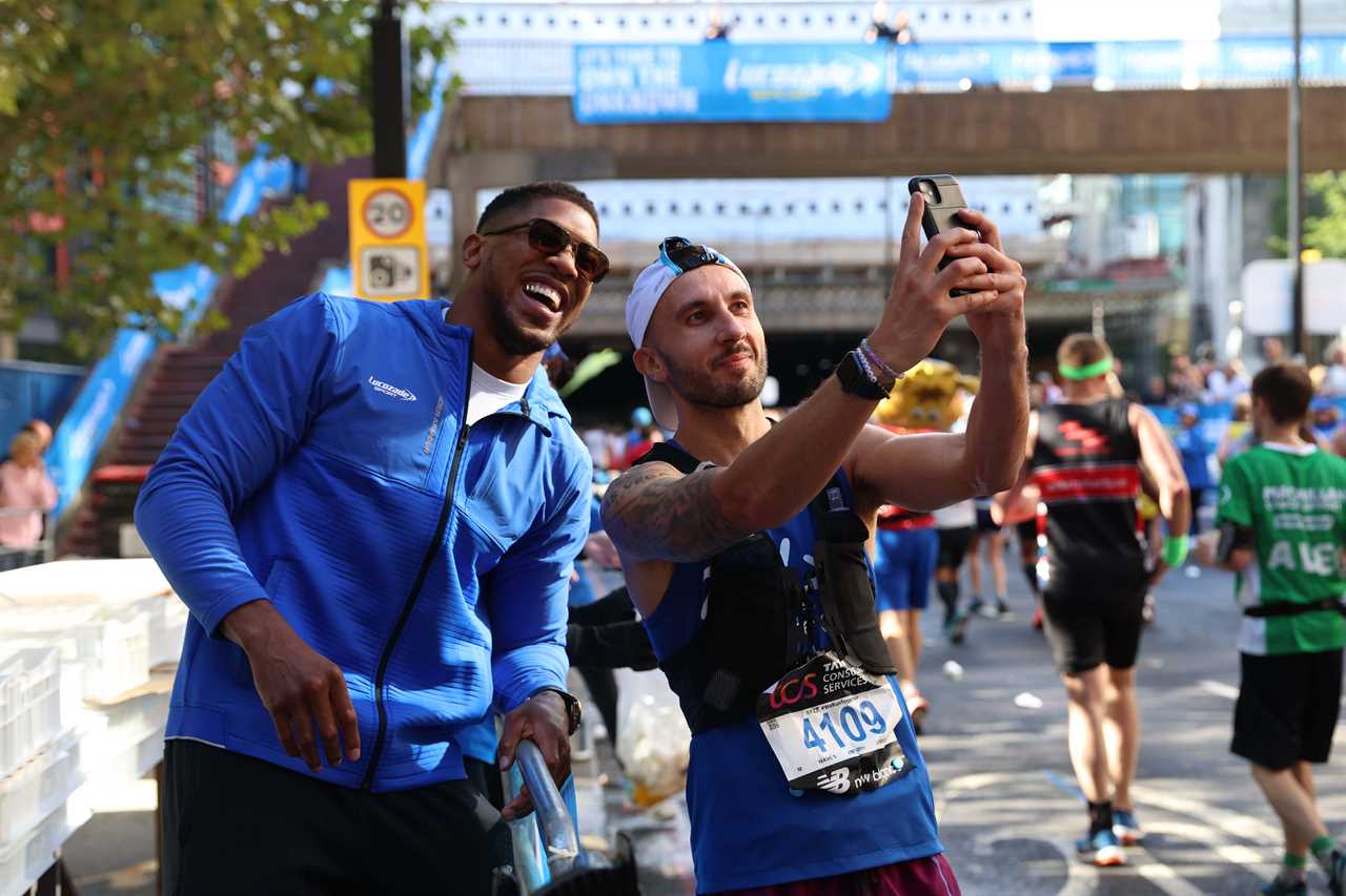 As Tyson Fury talks, Anthony Joshua gives drinks to London Marathon runners who stopped for selfies.