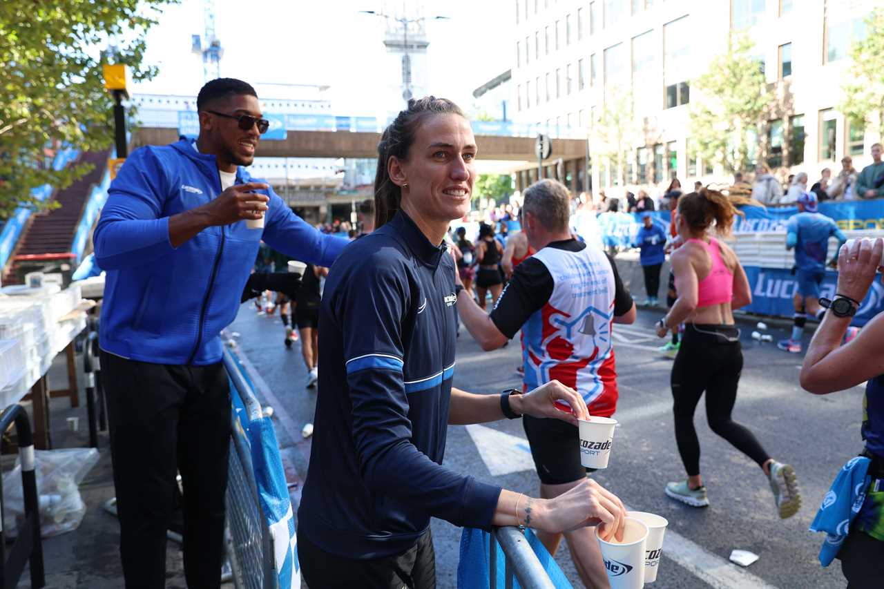 As Tyson Fury talks, Anthony Joshua gives drinks to London Marathon runners who stopped for selfies.