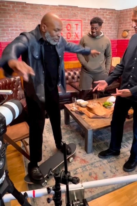 Mike Tyson, boxing legend, attempts to do a skateboard trick before falling backwards into an office chair