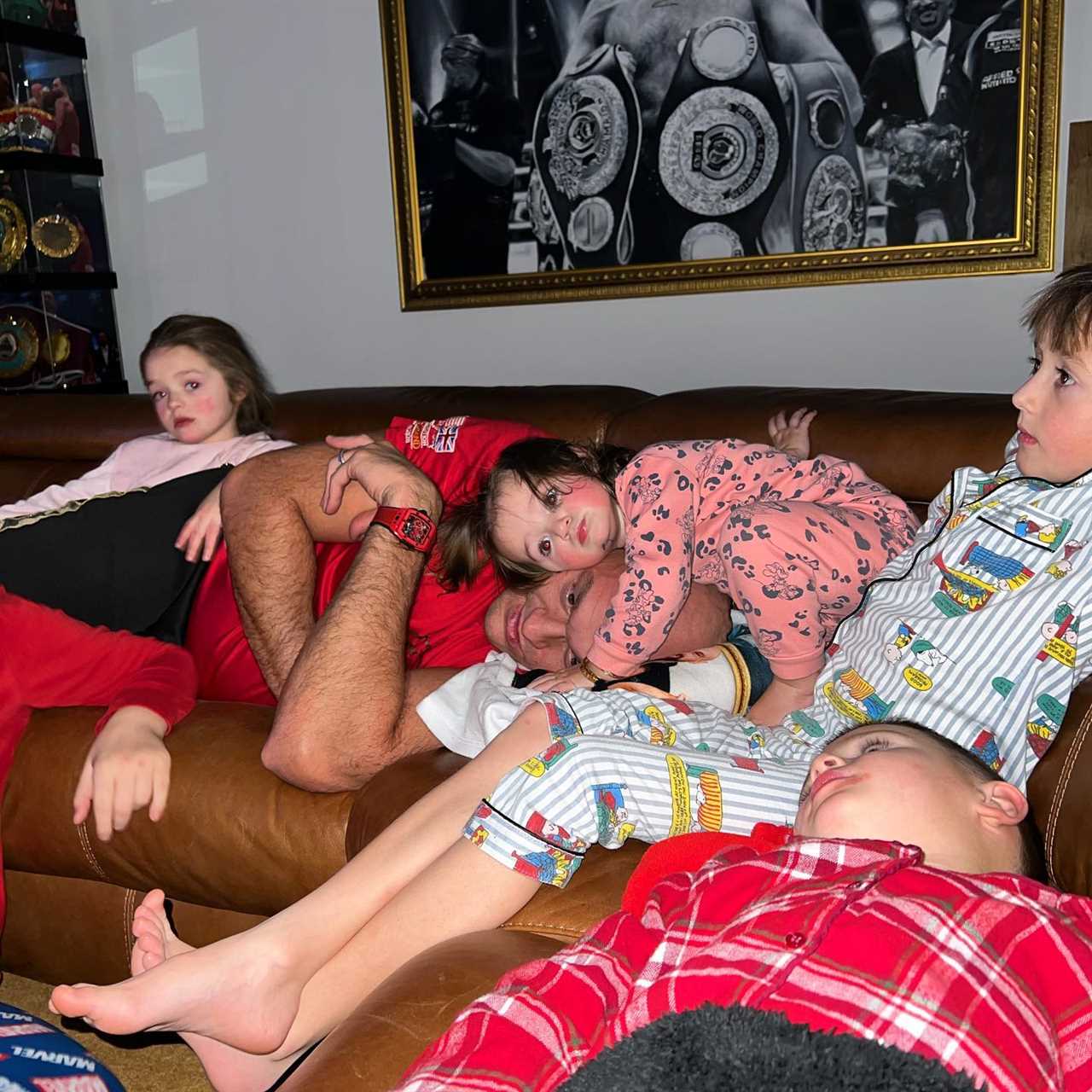 Tyson Fury is bundled up on the sofa by his loving children as Paris snaps sweet snap of their family movie night after Chisora win
