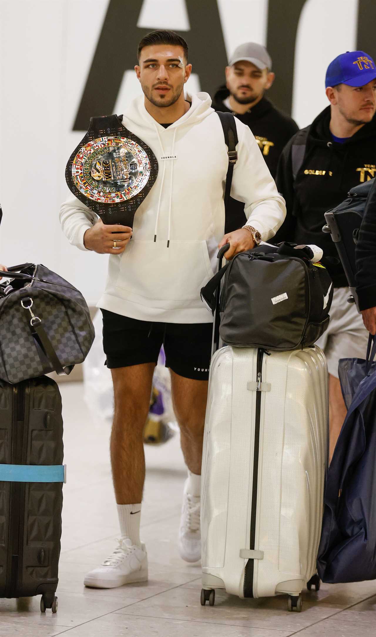 After a huge win over Jake Paul, Bruised Tommy Fury beams when he touches down at Heathrow together with dad John and brother Tyson.