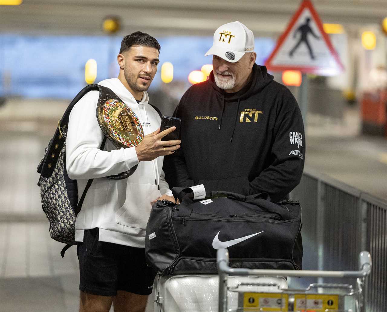After a huge win over Jake Paul, Bruised Tommy Fury beams when he touches down at Heathrow together with dad John and brother Tyson.