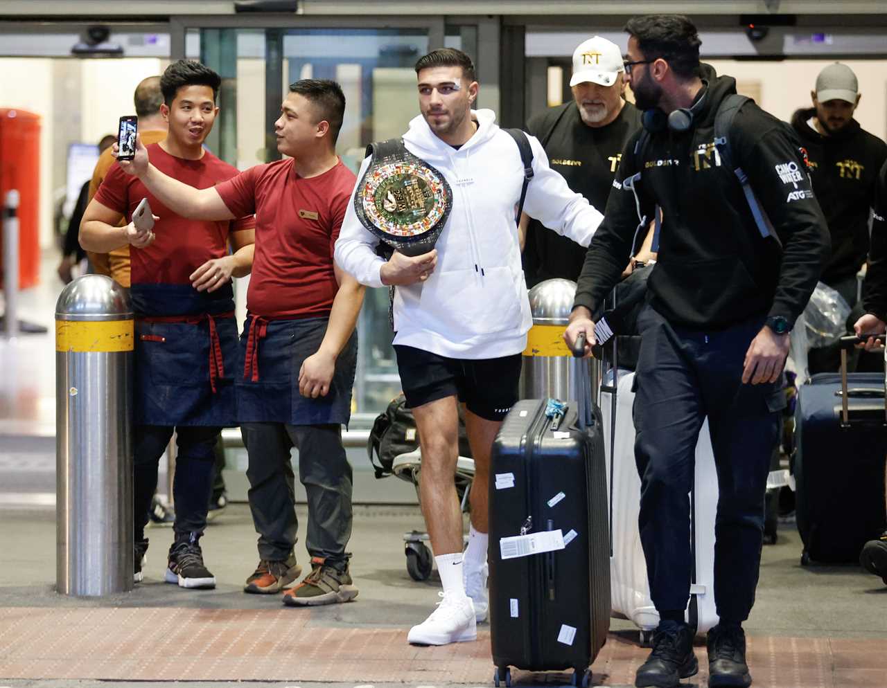 After a huge win over Jake Paul, Bruised Tommy Fury beams when he touches down at Heathrow together with dad John and brother Tyson.