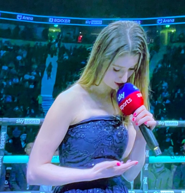 Television viewers see a singer reading the national anthem from her hand, before Lawrence Okolie's win for the'shambolic title'