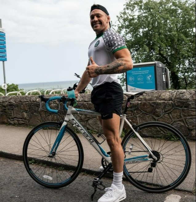 Conor McGregor gets back on his bicycle after he was hit by a car while cycling in Nigeria kit, then takes a dip in the ocean