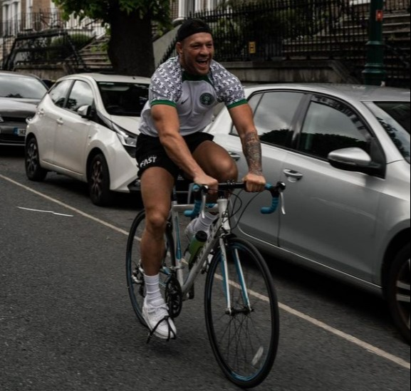 Conor McGregor gets back on his bicycle after he was hit by a car while cycling in Nigeria kit, then takes a dip in the ocean
