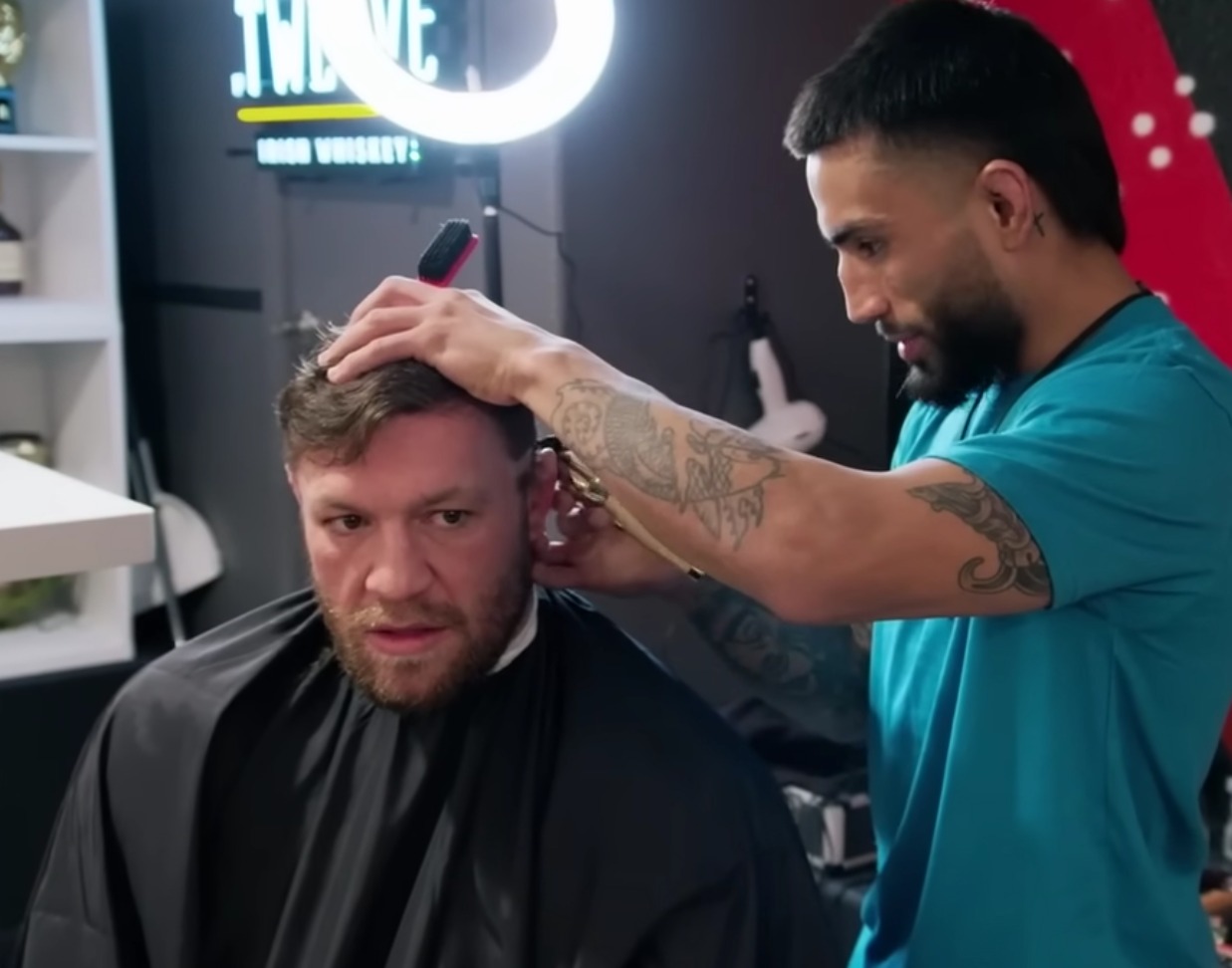 Fans can't stop but notice Conor McGregor looks bored as the barber talks on and on.