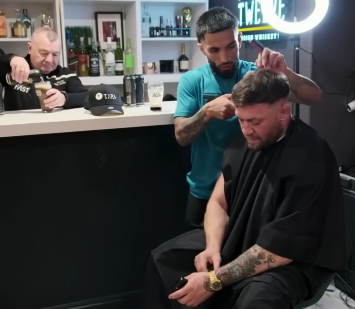 Fans can't stop but notice Conor McGregor looks bored as the barber talks on and on.