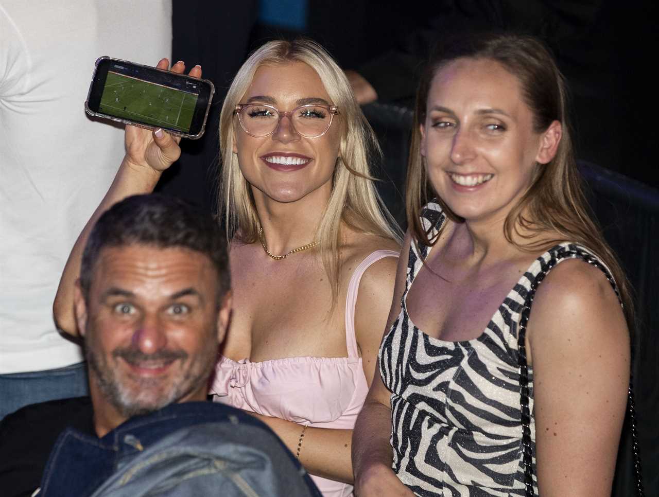 Elle Brooke, a Man City fan and treble winner at the boxing match, watches on her phone as she watches the treble victory