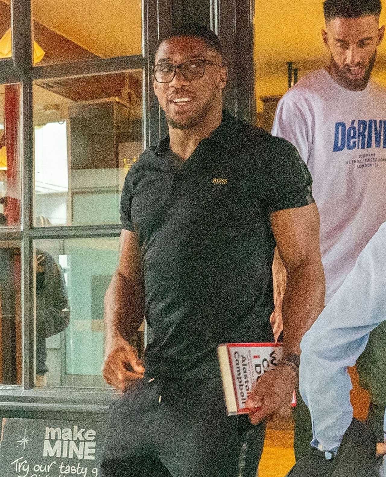 Anthony Joshua seen with a politics book while he meets his fans outside a restaurant