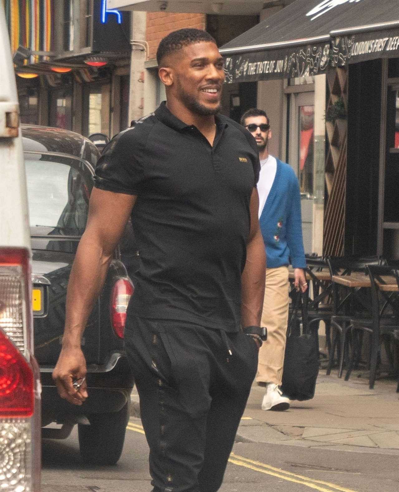 Anthony Joshua seen with a politics book while he meets his fans outside a restaurant